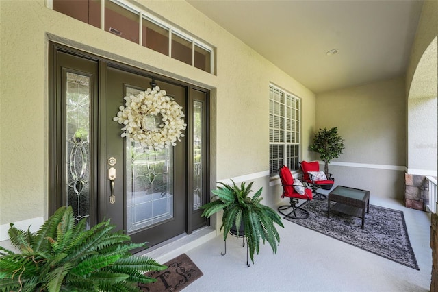 property entrance with stucco siding and a porch