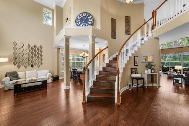 foyer featuring hardwood / wood-style floors, a notable chandelier, decorative columns, and plenty of natural light
