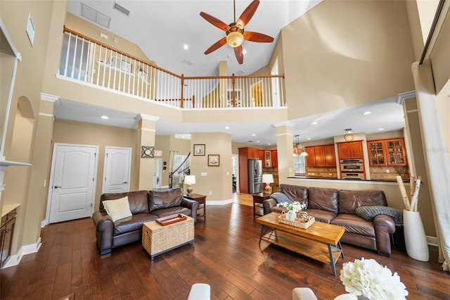 living room featuring visible vents, ornate columns, dark wood-type flooring, and a ceiling fan