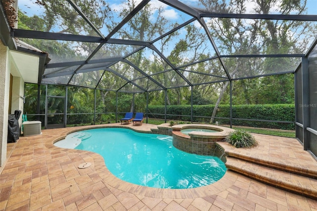view of pool with glass enclosure, a pool with connected hot tub, and a patio area