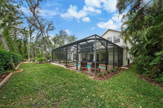 back of property with an outdoor pool, stucco siding, a patio, glass enclosure, and a yard