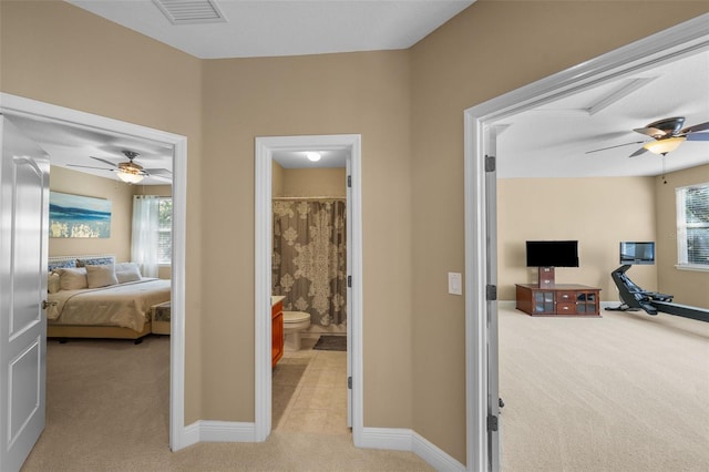 hall with light colored carpet, visible vents, and baseboards