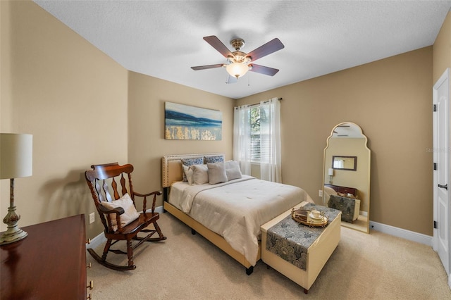bedroom featuring light colored carpet, ceiling fan, baseboards, and a textured ceiling