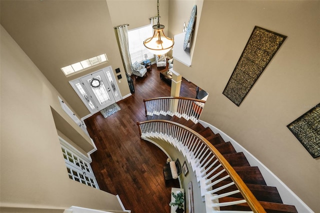 stairway featuring baseboards, wood finished floors, and a towering ceiling