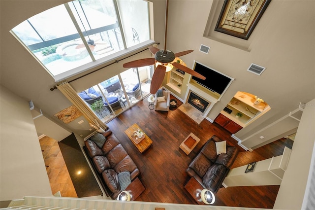 living room with visible vents, a high ceiling, wood finished floors, and ceiling fan