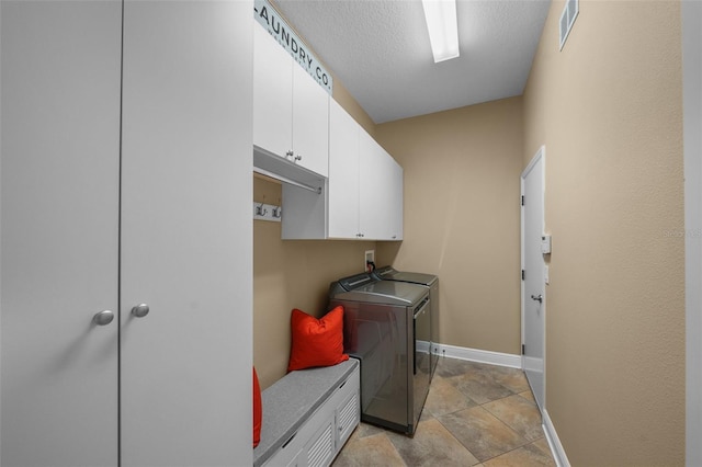 laundry area with baseboards, separate washer and dryer, a textured ceiling, visible vents, and cabinet space