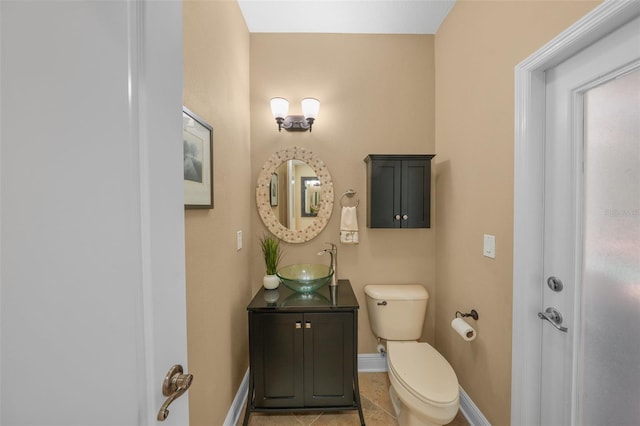 half bathroom featuring baseboards, toilet, vanity, and tile patterned floors