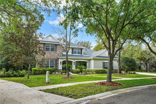 view of front facade with a front yard, stone siding, and stucco siding