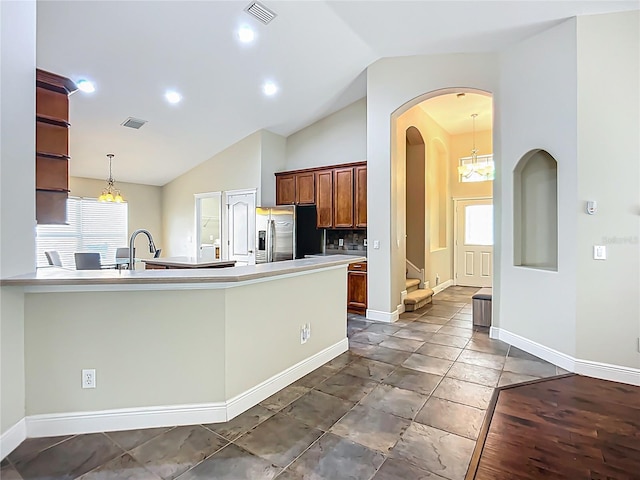 kitchen featuring vaulted ceiling, arched walkways, decorative light fixtures, stainless steel refrigerator with ice dispenser, and visible vents