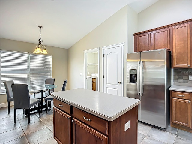 kitchen featuring a center island, stainless steel fridge, a chandelier, lofted ceiling, and pendant lighting