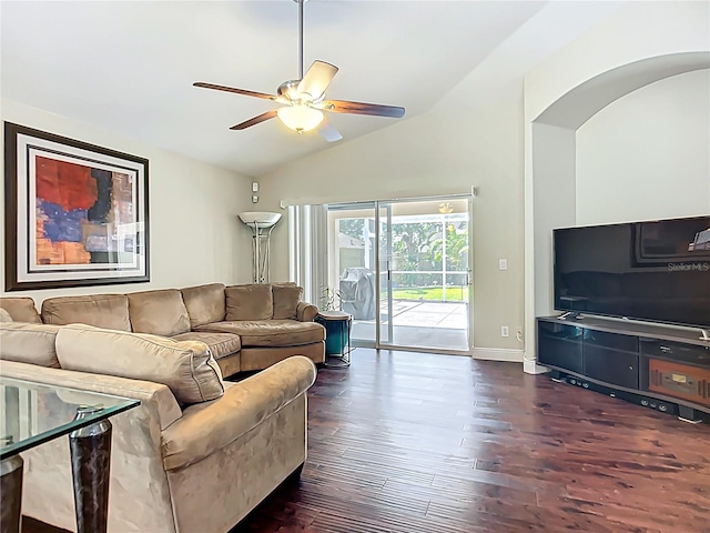 living area with vaulted ceiling, a ceiling fan, arched walkways, dark wood-type flooring, and baseboards