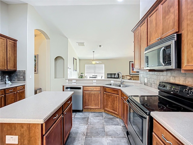 kitchen with stainless steel appliances, a peninsula, a sink, backsplash, and ceiling fan