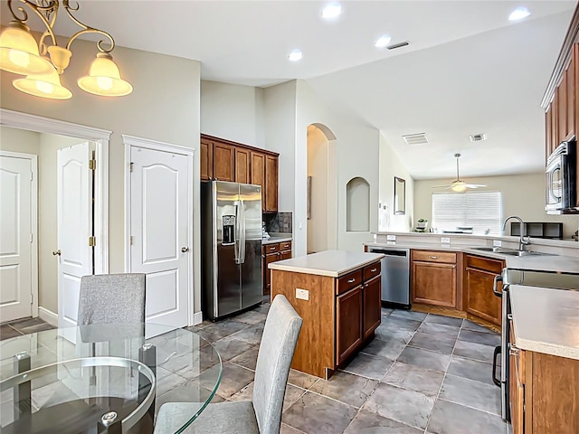 kitchen featuring a sink, arched walkways, stainless steel appliances, light countertops, and visible vents