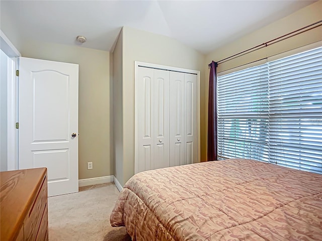 bedroom with light colored carpet, baseboards, and a closet