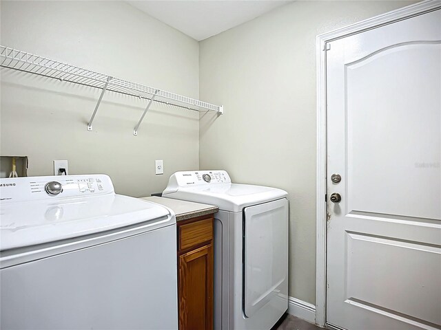 washroom with washing machine and clothes dryer and cabinet space