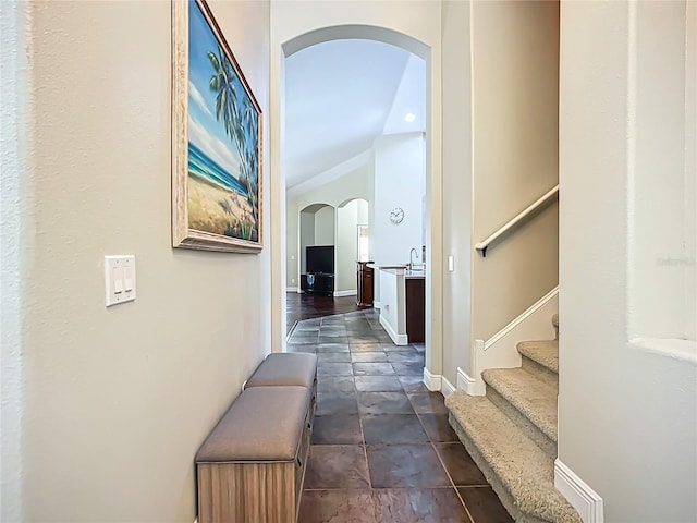 hall with stairway, arched walkways, vaulted ceiling, and baseboards