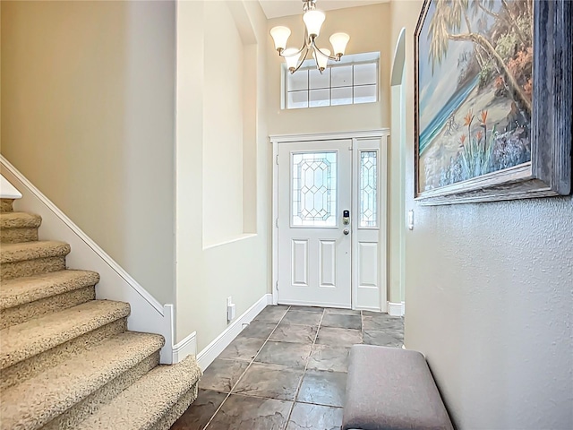 foyer featuring a chandelier, stairway, stone finish flooring, and baseboards