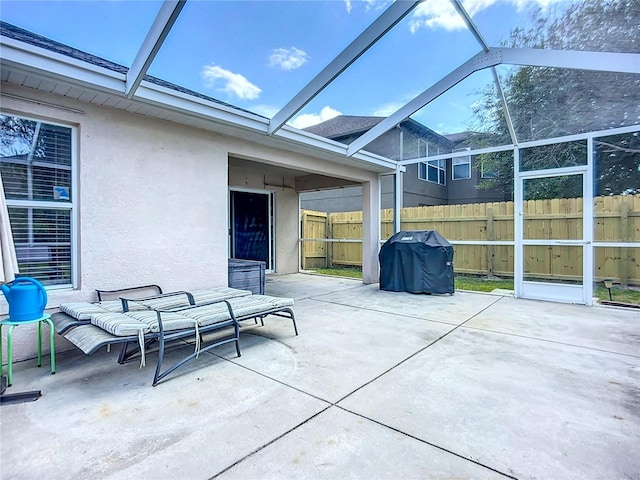 view of patio with glass enclosure, grilling area, and fence