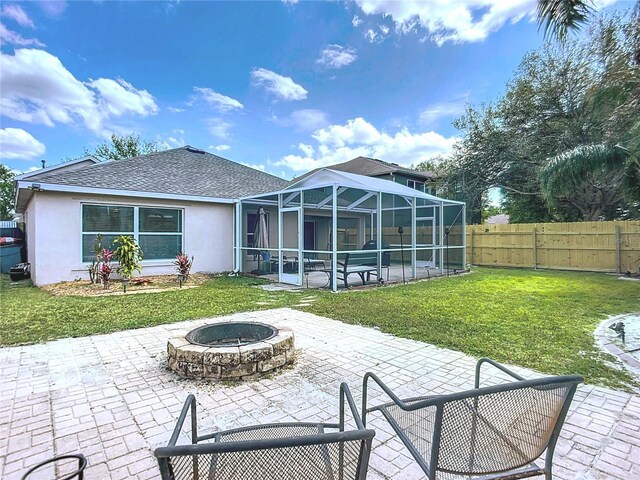 rear view of house featuring stucco siding, a lawn, an outdoor fire pit, and a patio