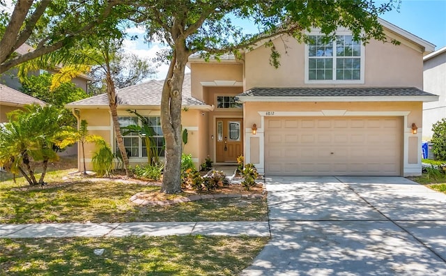 traditional-style house with stucco siding, driveway, and a garage