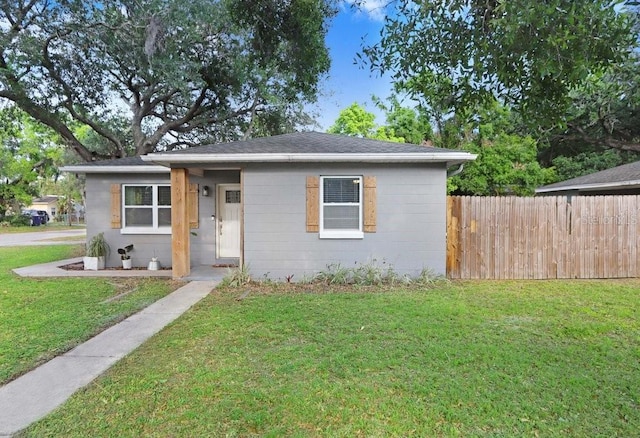 2001 E Idlewild Ave, Tampa, FL 33610 - bungalow featuring concrete block siding, fence, and a front lawn