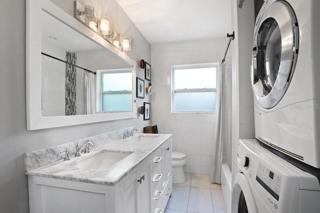 2001 E Idlewild Ave, Tampa, FL 33610 - bathroom with toilet, stacked washer / drying machine, a sink, and tile patterned flooring