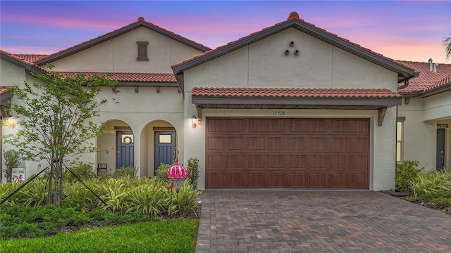 17228 Holly Well Ave, Wimauma, FL 33598 - mediterranean / spanish-style house featuring decorative driveway, a tile roof, an attached garage, and stucco siding