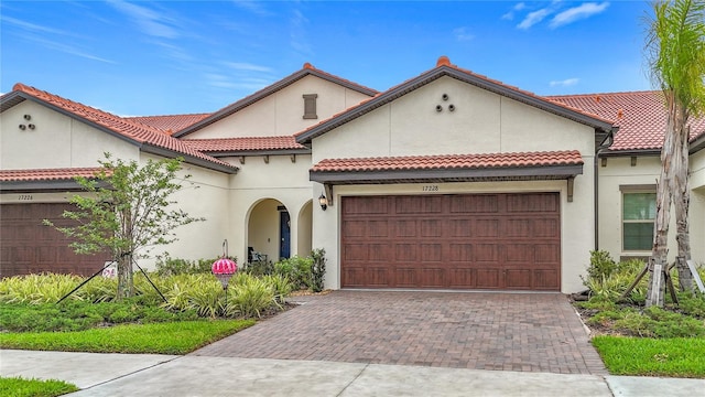 17228 Holly Well Ave, Wimauma, FL 33598 - mediterranean / spanish home featuring an attached garage, decorative driveway, stucco siding, and a tiled roof