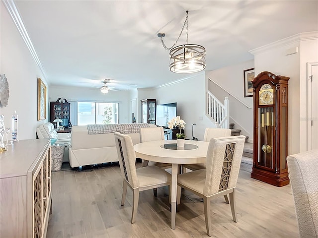 17228 Holly Well Ave, Wimauma, FL 33598 - dining room with ornamental molding, stairway, light wood finished floors, a ceiling fan, and a chandelier