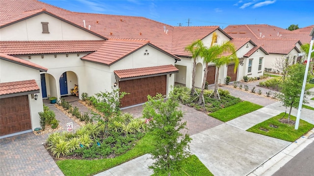 17228 Holly Well Ave, Wimauma, FL 33598 - mediterranean / spanish house featuring an attached garage, decorative driveway, stucco siding, and a tile roof