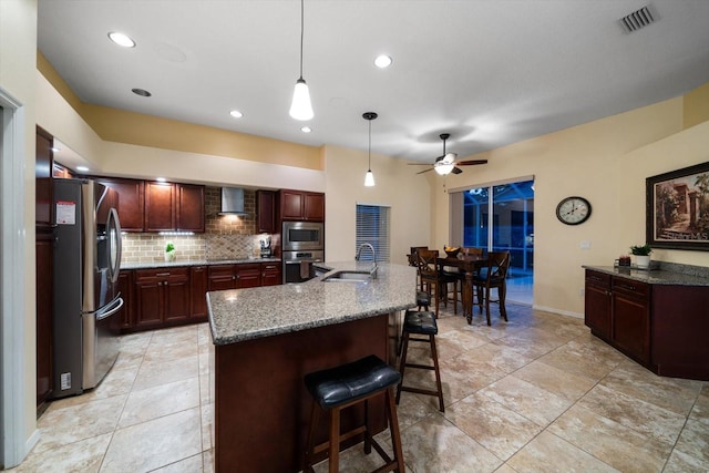 kitchen featuring a sink, decorative backsplash, stainless steel appliances, wall chimney exhaust hood, and visible vents