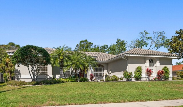 view of front of home featuring stucco siding, a tile roof, and a front yard
