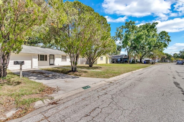 129 NW Lincoln Cir N, Saint Petersburg, FL 33702 - ranch-style home with aphalt driveway, a front yard, and a garage