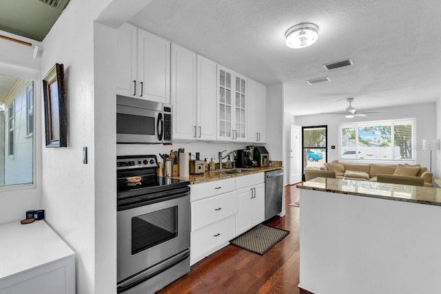 129 NW Lincoln Cir N, Saint Petersburg, FL 33702 - kitchen featuring white cabinets, stainless steel appliances, dark wood-style floors, visible vents, and glass insert cabinets
