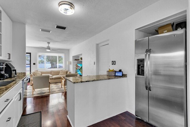 129 NW Lincoln Cir N, Saint Petersburg, FL 33702 - kitchen with visible vents, dark stone counters, a textured ceiling, stainless steel refrigerator with ice dispenser, and white cabinetry