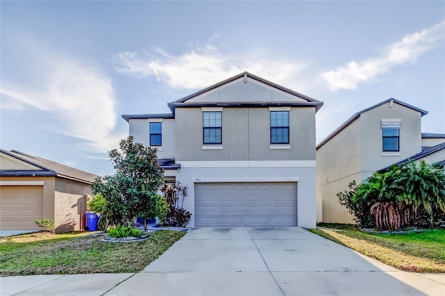 traditional-style home featuring an attached garage, concrete driveway, and stucco siding