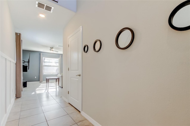 hall featuring visible vents, baseboards, and light tile patterned floors