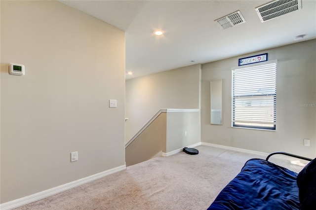 unfurnished room with visible vents, baseboards, an upstairs landing, and carpet floors