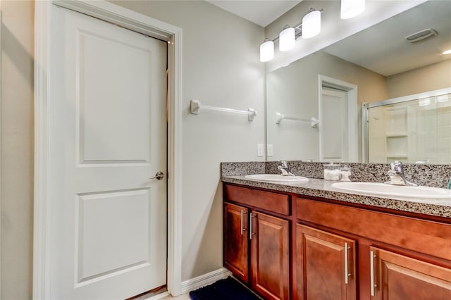 bathroom with a sink, visible vents, double vanity, and a shower with shower door
