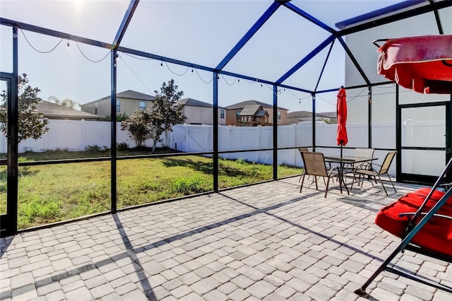 view of patio / terrace featuring a fenced backyard, a residential view, and glass enclosure