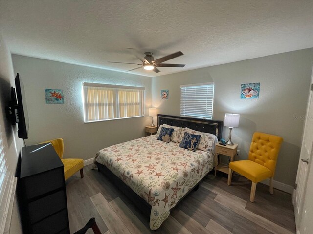 bedroom with wood finished floors, baseboards, a textured ceiling, and a ceiling fan