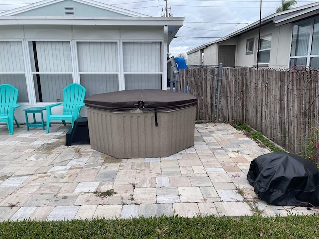 view of patio featuring a hot tub and fence