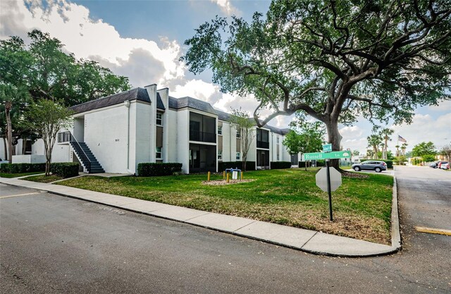 view of front of property featuring stucco siding, a front lawn, and stairway