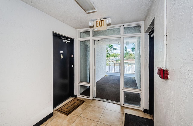 doorway featuring light tile patterned flooring, a textured ceiling, and a textured wall
