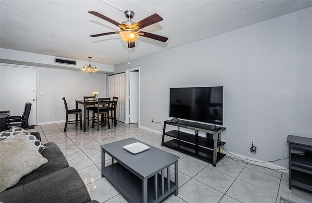 living area with visible vents, ceiling fan with notable chandelier, a textured ceiling, and marble finish floor