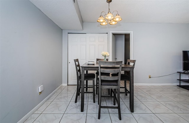 dining room with a textured ceiling, a notable chandelier, baseboards, and marble finish floor