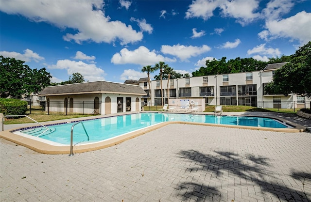 community pool with a patio area and fence