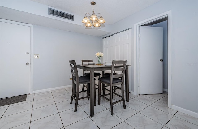 dining space featuring visible vents, a textured ceiling, baseboards, and an inviting chandelier