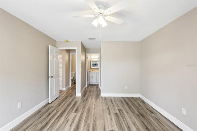 1203 16th Cir SE, Largo, FL 33771 - unfurnished bedroom featuring light wood-style flooring, baseboards, ceiling fan, and ensuite bathroom