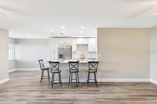1203 16th Cir SE, Largo, FL 33771 - kitchen featuring stainless steel fridge, white cabinetry, a kitchen bar, recessed lighting, and backsplash